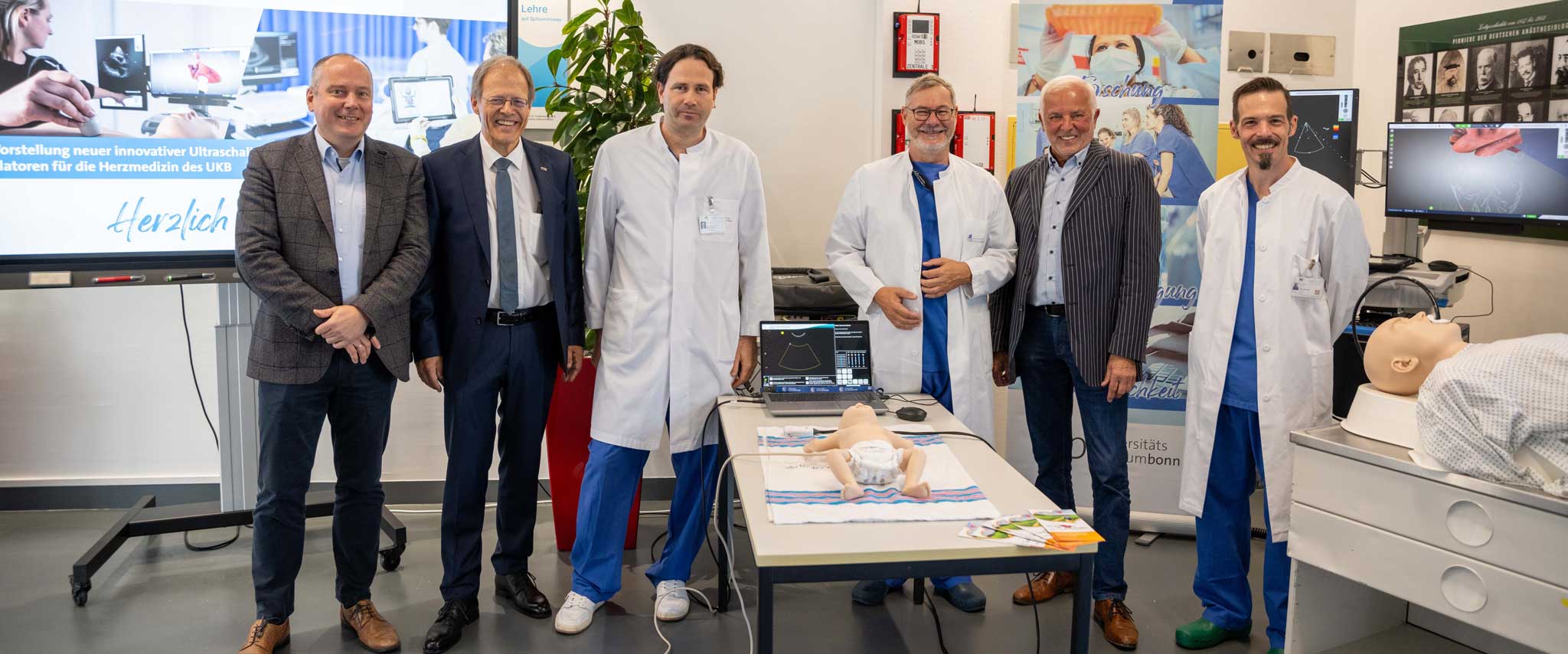 Prof. Bernd Weber, Dekan der Medizinischen Fakultät der Universität Bonn, Prof. Wolfgang Holzgreve, Ärztlicher Direktor und Vorstandsvorsitzender des UKB, Prof. Mark Coburn, Direktor der Klinik für Anästhesiologie und Operative Intensivmedizin des UKB, Prof. Ehrenfried Schindler, Sektionsleiter der Kinderanästhesiologie an der Klinik für Anästhesiologie und Operative Intensivmedizin des UKB, Günter Mies, 1. Vorsitzender des Vereins „Kleine Herzen Westerwald e. V.“ und Marc Rohner, Oberarzt an der Klinik für Anästhesiologie und Operative Intensivmedizin des UKB; bei der offiziellen Präsentation der Simulatoren